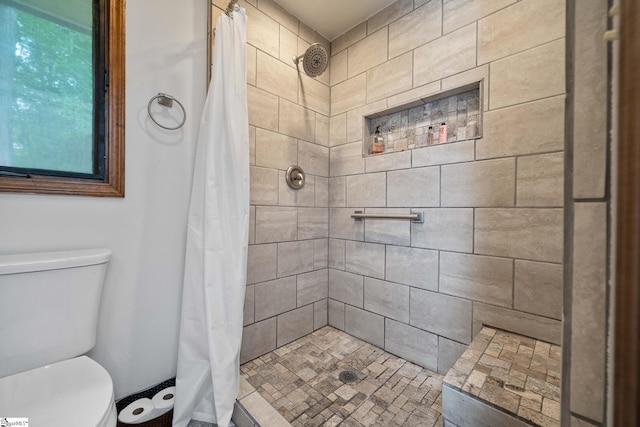 bathroom featuring toilet and a tile shower