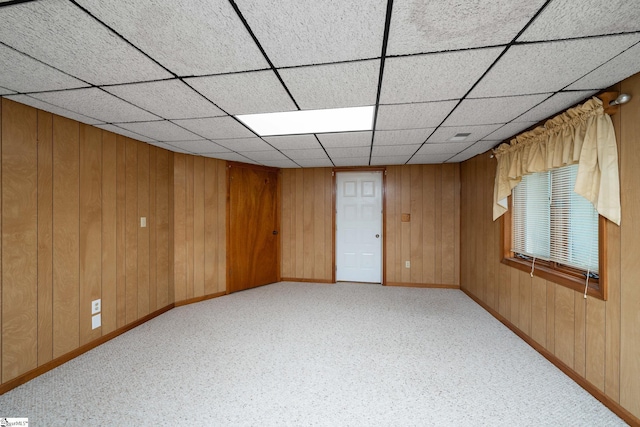 unfurnished room featuring wooden walls, baseboards, and carpet floors