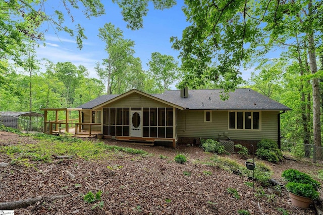 rear view of property with a sunroom, a shingled roof, and fence