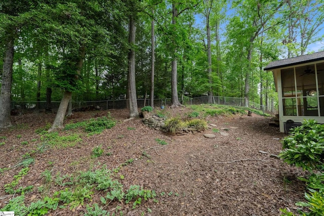 view of yard with ceiling fan, a sunroom, and fence
