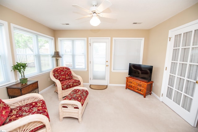 living area featuring carpet flooring, baseboards, a ceiling fan, and visible vents