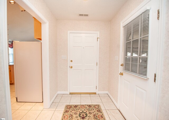 doorway to outside with baseboards, light tile patterned floors, and visible vents