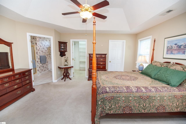 bedroom with baseboards, ensuite bathroom, ceiling fan, visible vents, and light colored carpet