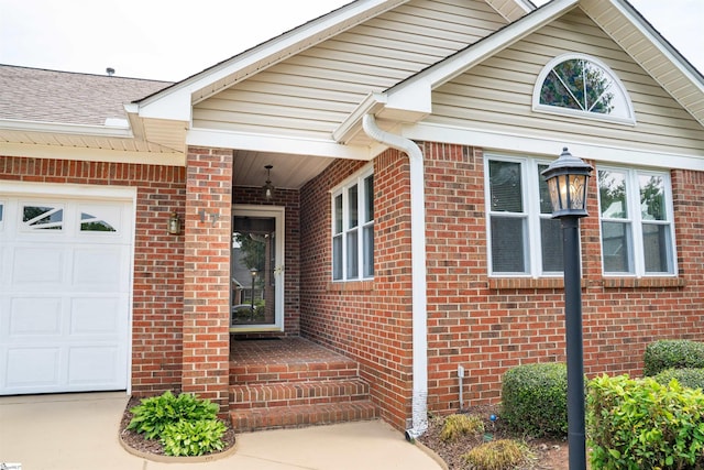 entrance to property with brick siding and a garage