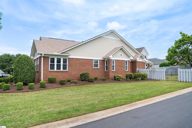 ranch-style home featuring a front yard, brick siding, a shingled roof, and fence
