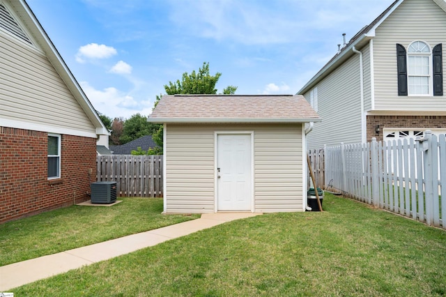 view of outbuilding with a fenced backyard, an outdoor structure, and central air condition unit