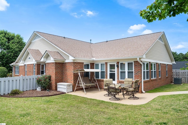 rear view of house featuring a yard, fence, a shingled roof, brick siding, and a patio area