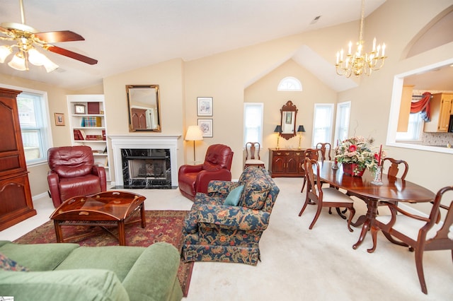 living room featuring vaulted ceiling, light carpet, a fireplace, and ceiling fan with notable chandelier