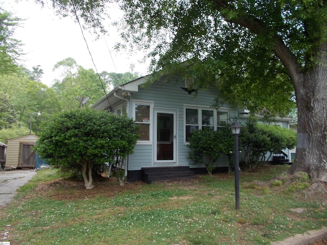 33 School St, Enoree, SC 29335 - shotgun-style home with entry steps, a front lawn, a shed, and an outdoor structure