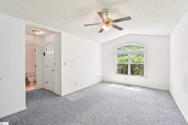 empty room featuring ceiling fan, lofted ceiling, carpet flooring, and baseboards