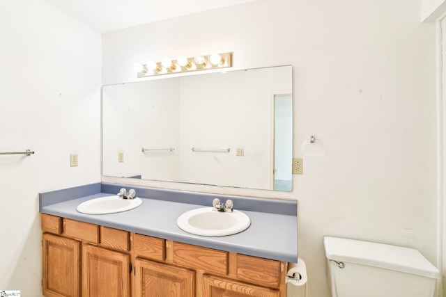 bathroom featuring double vanity, toilet, and a sink