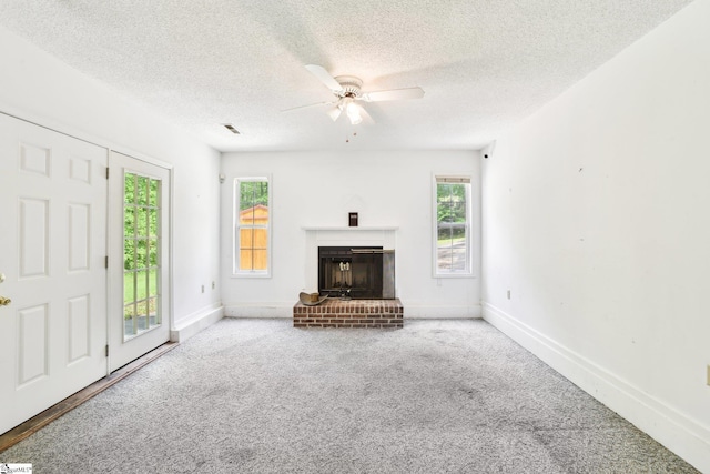 unfurnished living room featuring a fireplace, carpet, a ceiling fan, and plenty of natural light