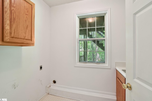 laundry room featuring baseboards, hookup for an electric dryer, and cabinet space