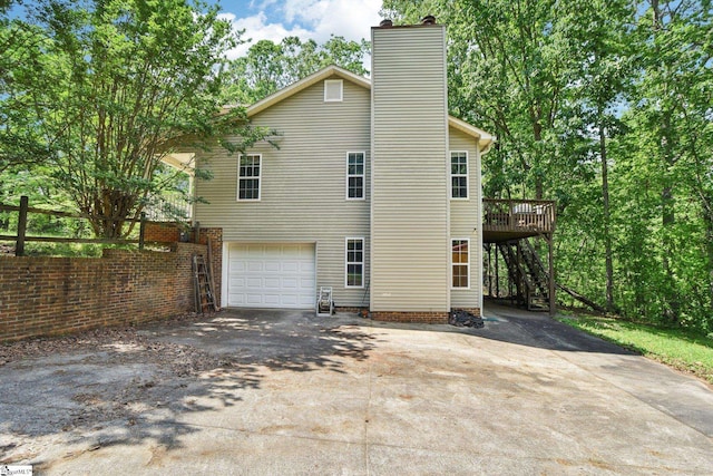 view of side of property featuring aphalt driveway, a deck, a garage, stairway, and a chimney