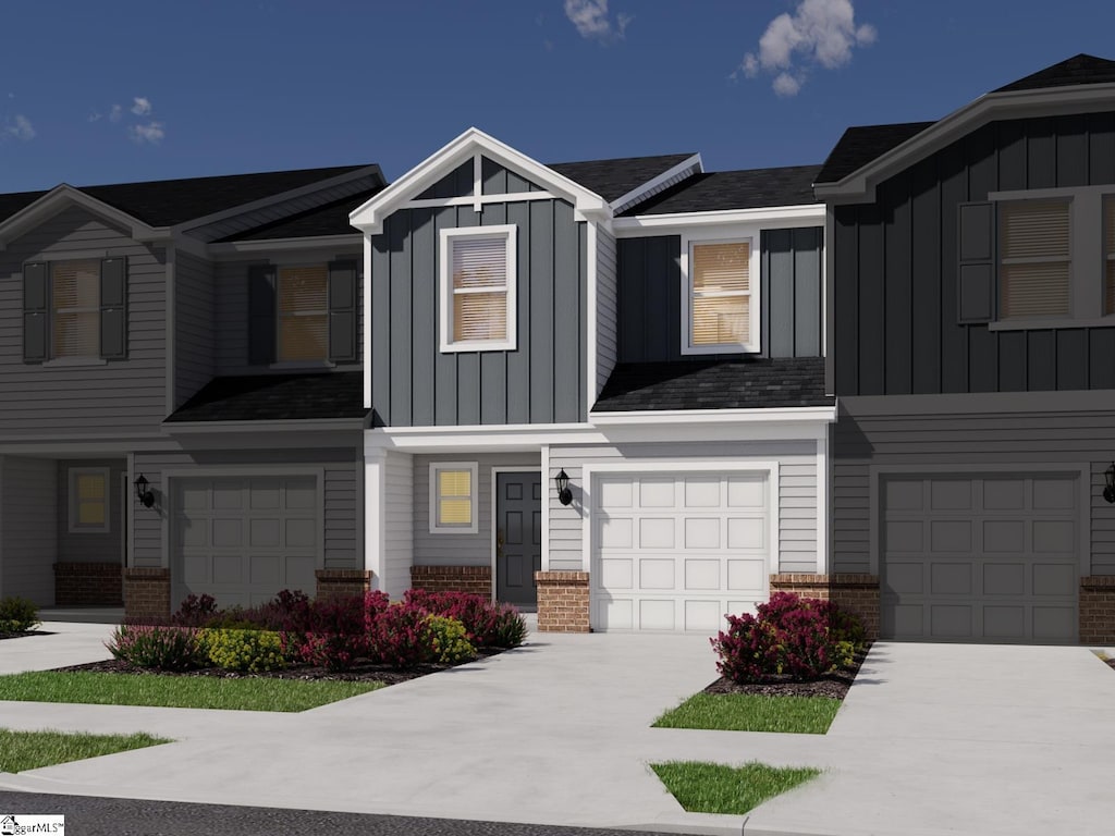 view of front of home featuring an attached garage, board and batten siding, brick siding, and driveway