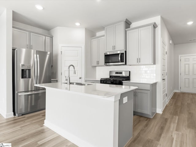 112 Arrow Ct, Greer, SC 29651 - kitchen featuring stainless steel appliances, a center island with sink, gray cabinetry, light wood finished floors, and light countertops