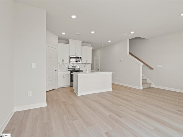124 Arrow Ct, Greer, SC 29651 - kitchen featuring stainless steel appliances, light wood-style floors, decorative backsplash, white cabinetry, and open floor plan