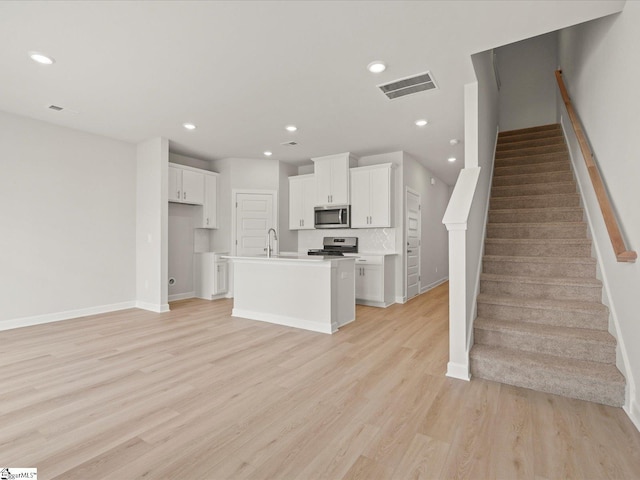 124 Arrow Ct, Greer, SC 29651 - kitchen featuring stainless steel appliances, white cabinetry, light wood-style floors, an island with sink, and recessed lighting
