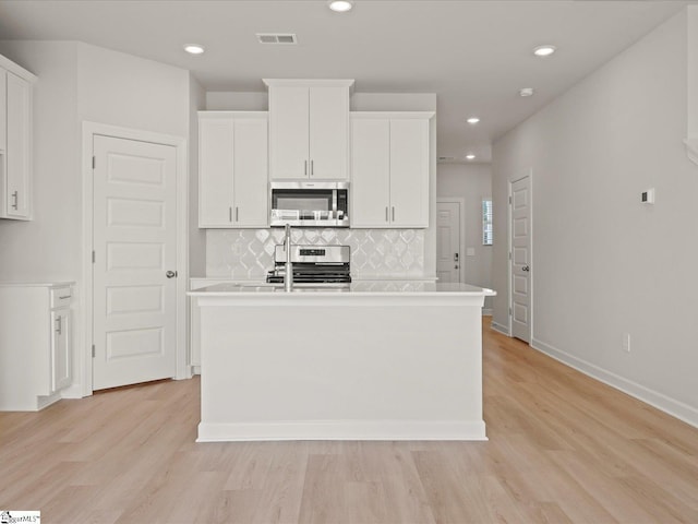 124 Arrow Ct, Greer, SC 29651 - kitchen featuring stainless steel appliances, a center island with sink, white cabinets, light wood-style flooring, and backsplash