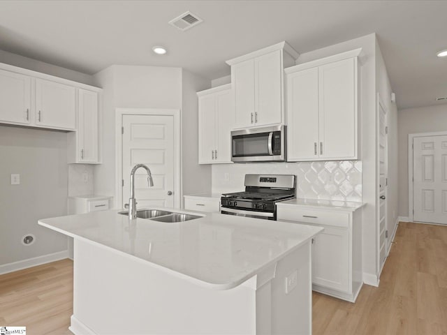 124 Arrow Ct, Greer, SC 29651 - kitchen featuring appliances with stainless steel finishes, an island with sink, white cabinets, light wood finished floors, and recessed lighting