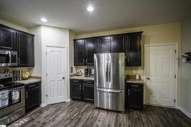 kitchen with dark wood-style flooring, stainless steel appliances, recessed lighting, and light stone countertops