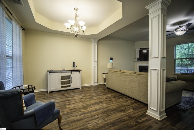 living area featuring baseboards, dark wood-style floors, visible vents, and decorative columns