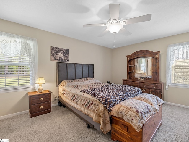 bedroom with light carpet, baseboards, and a ceiling fan