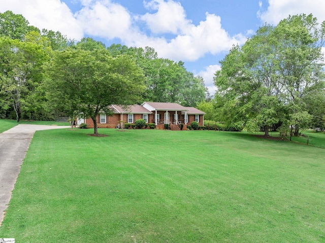 view of front of property featuring covered porch, brick siding, driveway, and a front yard
