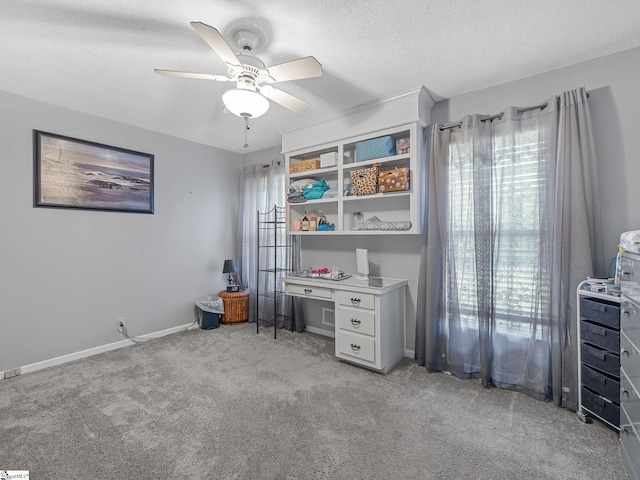 office area with a textured ceiling, baseboards, ceiling fan, and light colored carpet