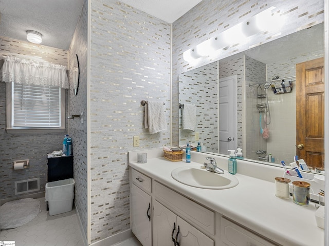 full bath featuring vanity, tile patterned flooring, visible vents, and a tile shower