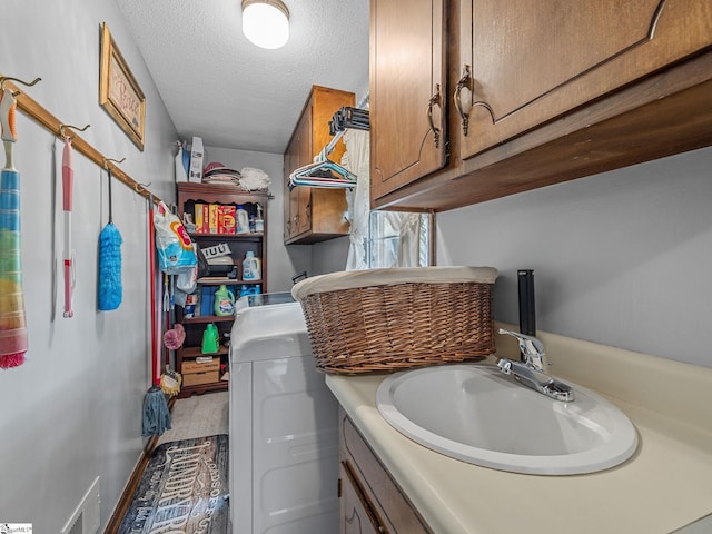 laundry area with a textured ceiling, visible vents, and a sink