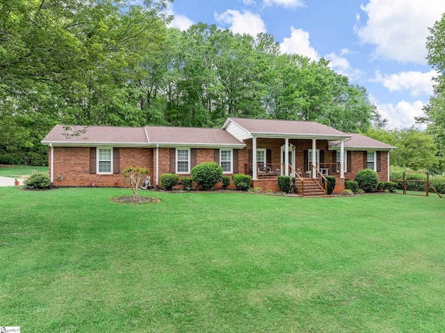 ranch-style home featuring a front yard, brick siding, and covered porch
