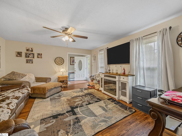 living area with a textured ceiling, wood finished floors, and a ceiling fan