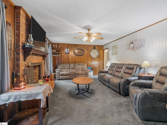 living area with wood walls, a textured ceiling, a brick fireplace, carpet floors, and a ceiling fan