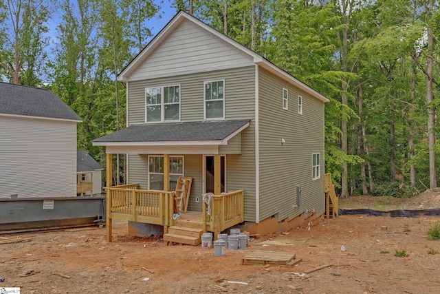 rear view of property with a deck and roof with shingles