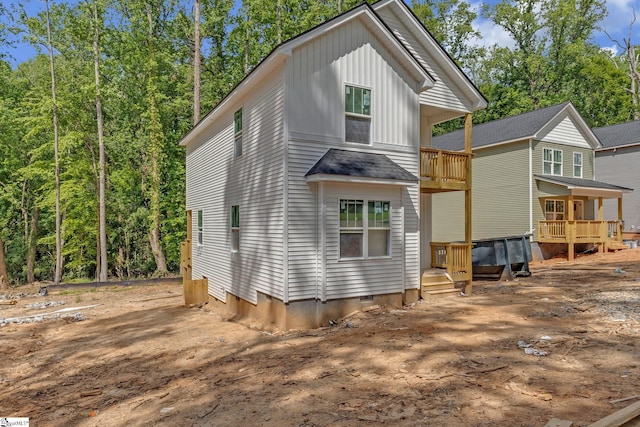 rear view of property with board and batten siding and a balcony