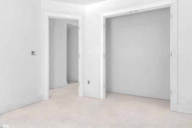 unfurnished bedroom with concrete flooring and a closet