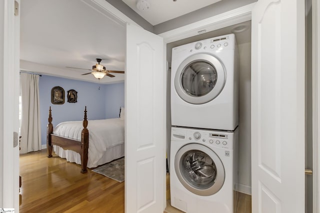 washroom featuring laundry area, stacked washer and dryer, a ceiling fan, baseboards, and light wood-style floors