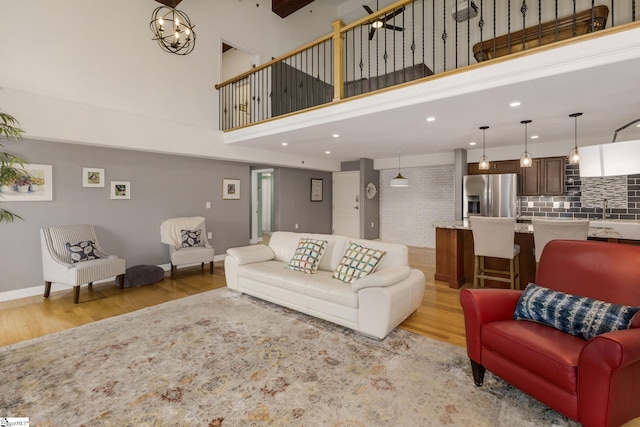 living area featuring baseboards, light wood finished floors, recessed lighting, and a towering ceiling