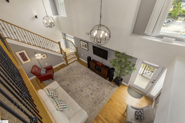living area with stairs, a notable chandelier, plenty of natural light, and wood finished floors
