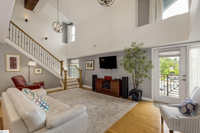 living area featuring a chandelier, a wealth of natural light, stairway, and a towering ceiling