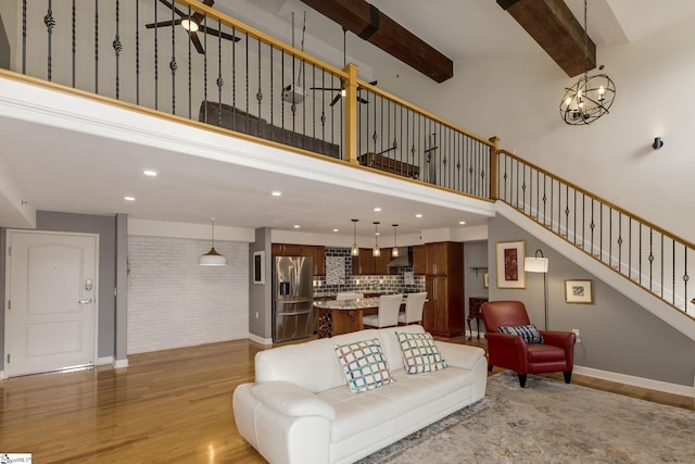 living area with a high ceiling, stairway, baseboards, light wood-style floors, and recessed lighting