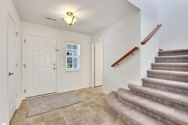 entrance foyer featuring visible vents, baseboards, stone finish flooring, and stairway