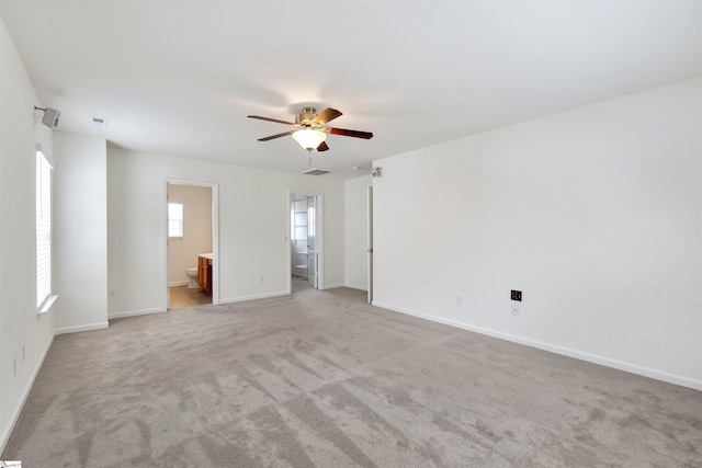 empty room with light carpet, baseboards, a ceiling fan, and visible vents