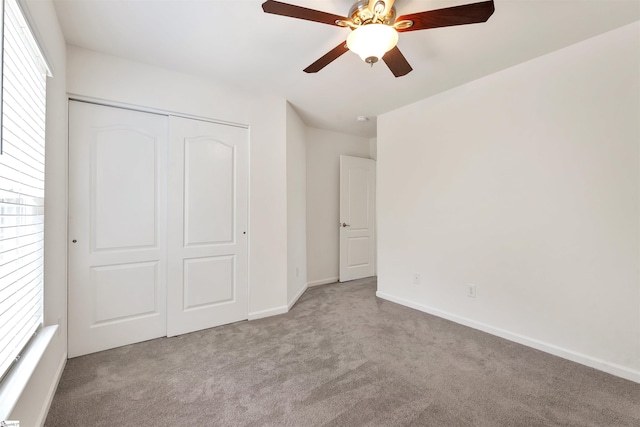 unfurnished bedroom featuring carpet, a closet, baseboards, and multiple windows