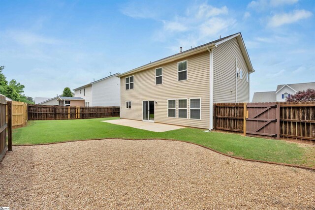 back of house featuring a lawn, a patio area, and a fenced backyard