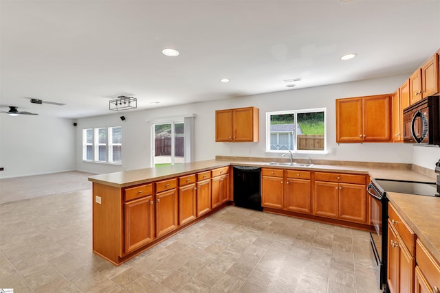 kitchen with a sink, a peninsula, brown cabinetry, and black appliances