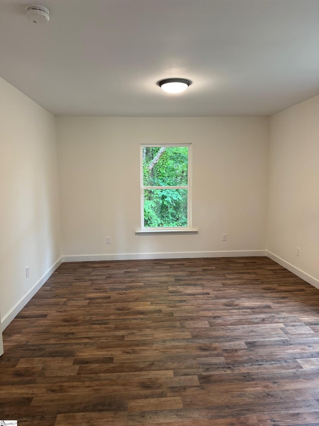 empty room featuring dark wood-type flooring and baseboards