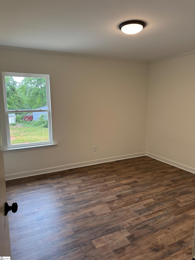 spare room featuring baseboards, dark wood finished floors, and crown molding
