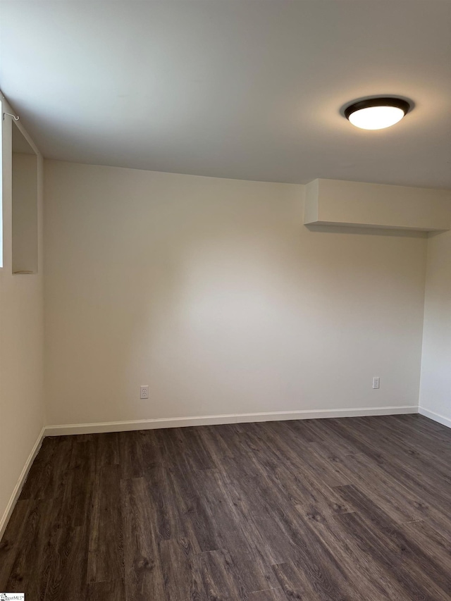 empty room featuring baseboards and dark wood-style floors